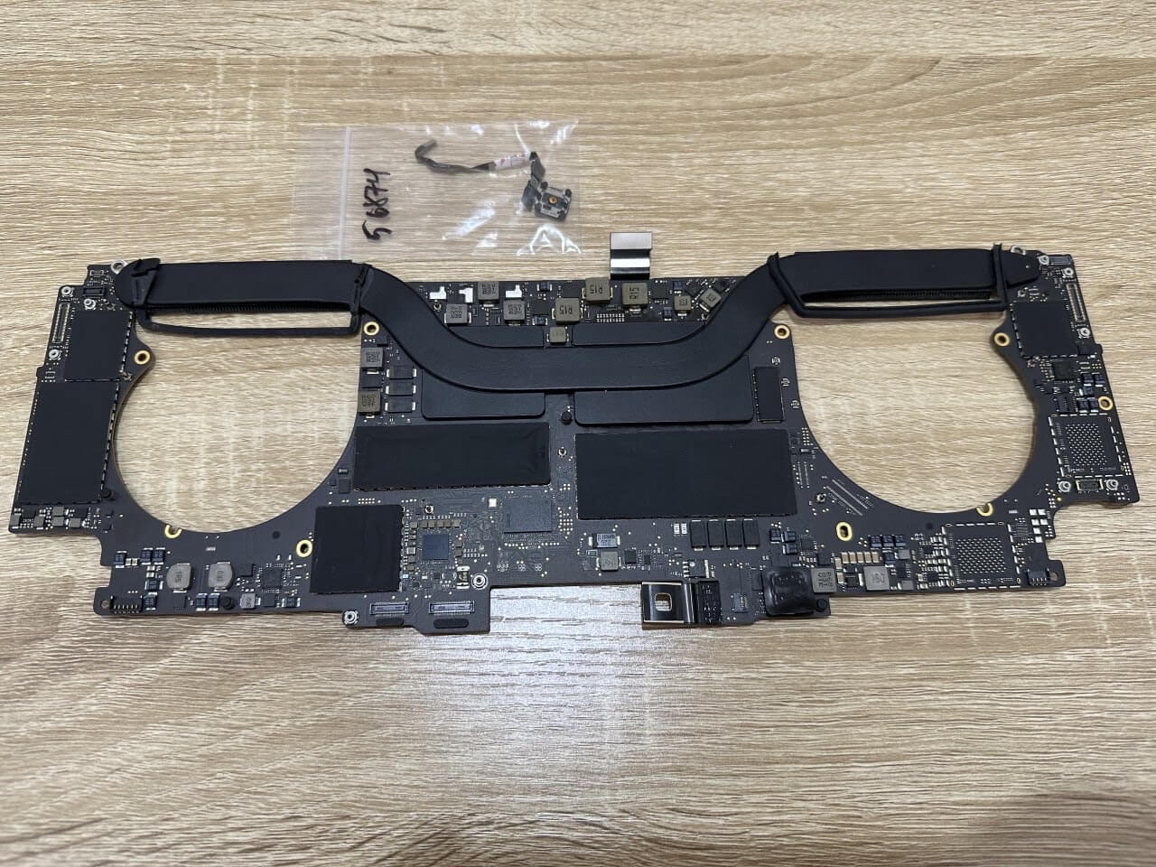 Second view of the MacBook motherboard during board-level repair for a charging problem.